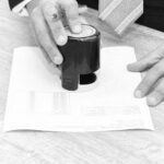 刑事裁判の略式命令をイメージした書類に押印する手元の白黒写真