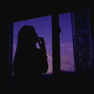 窓の外を見ながら顎に手を当てて考え込む人物